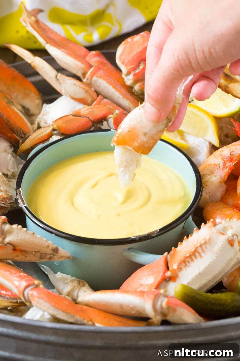 A small bowl of creamy mustard seafood dipping sauce placed elegantly on a serving platter alongside fresh crab, inviting diners.