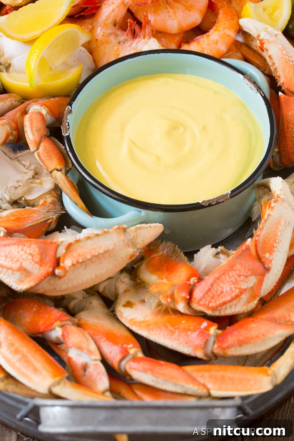 Shrimp, crab, and lemon wedges beautifully arranged on a platter, with a small bowl of yellow seafood mustard sauce ready for dipping.