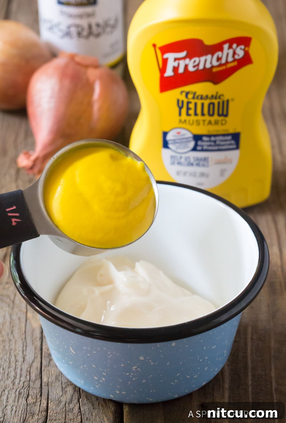Close-up shot of hands stirring the ingredients for Spicy Mustard Seafood Sauce in a mixing bowl.