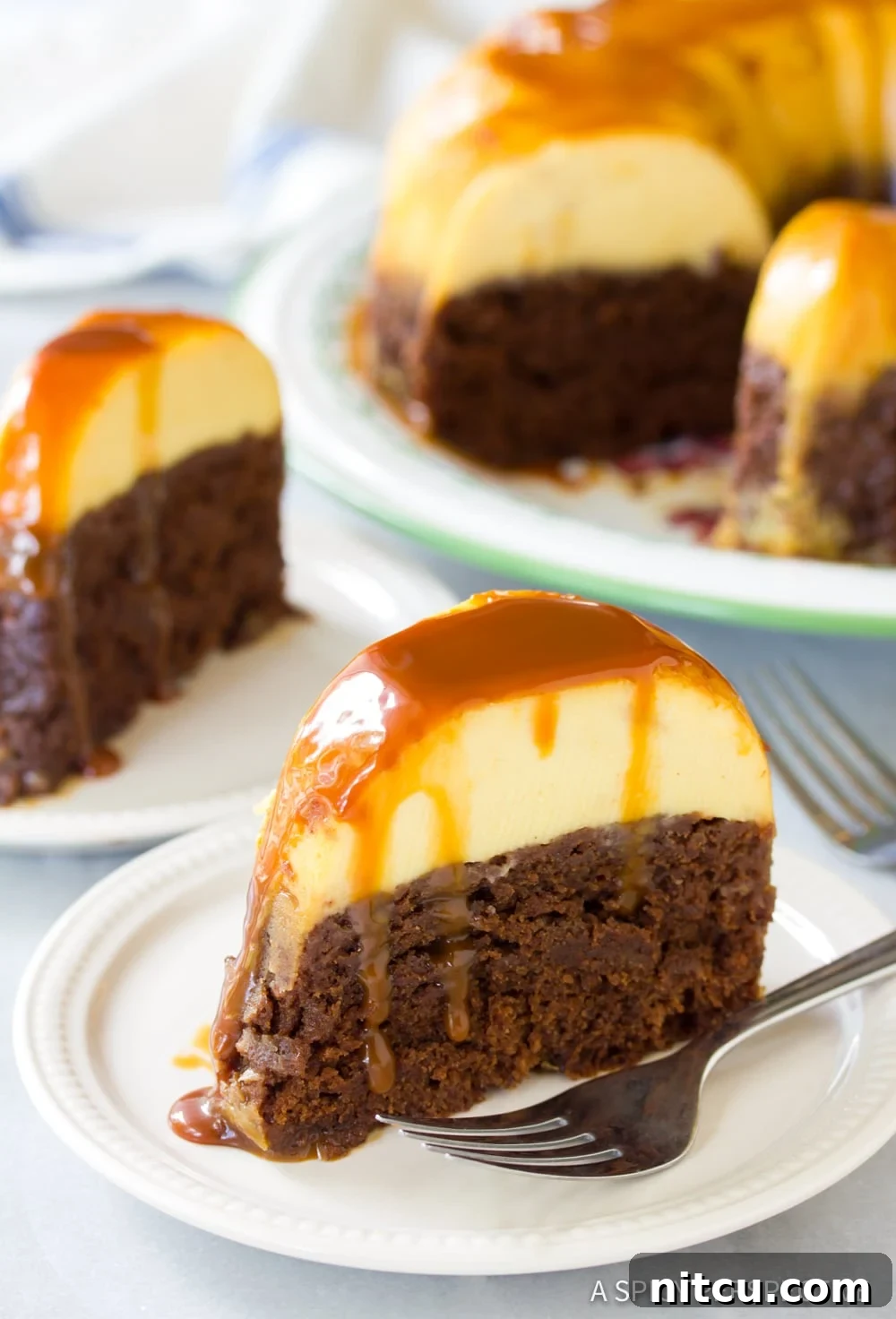 Individual slices of Chocoflan Impossible Cake on dessert plates, with the rest of the cake blurred in the background.