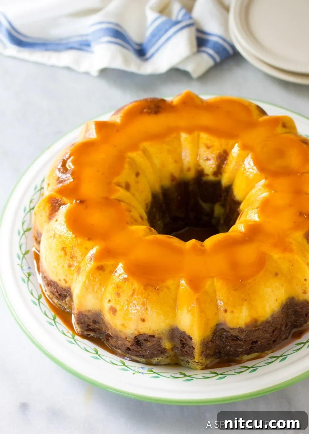 A freshly baked Mexican Chocoflan Impossible Cake, inverted onto a serving platter and glistening with cajeta caramel sauce.