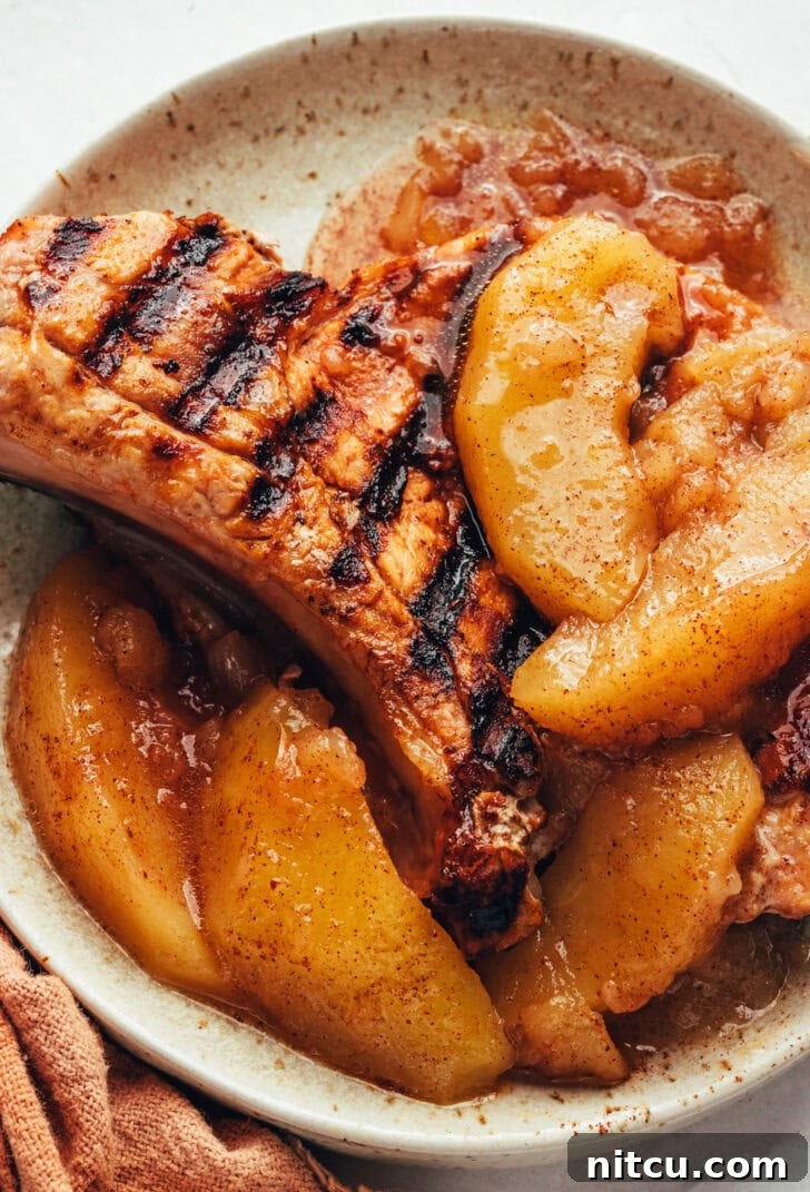 cinnamon apples on top of a grilled pork chop on a white plate. 