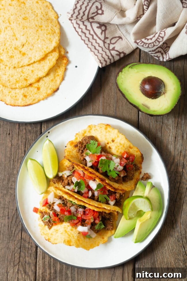 Overhead shot of three tacos on a plate made with low carb tortillas, vibrant with fresh toppings.