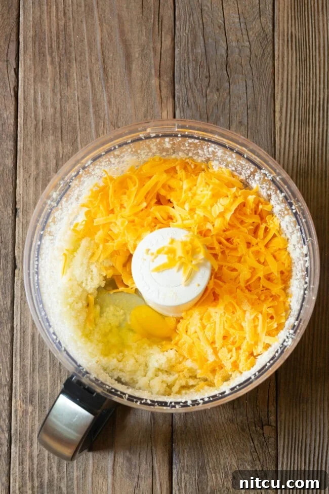 Cauliflower florets, shredded cheese, eggs, and spices ready to be processed.