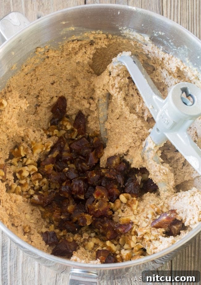 Breakfast oatmeal bar mixture being blended in a food processor with dates and nuts on top, indicating the mixing stage.