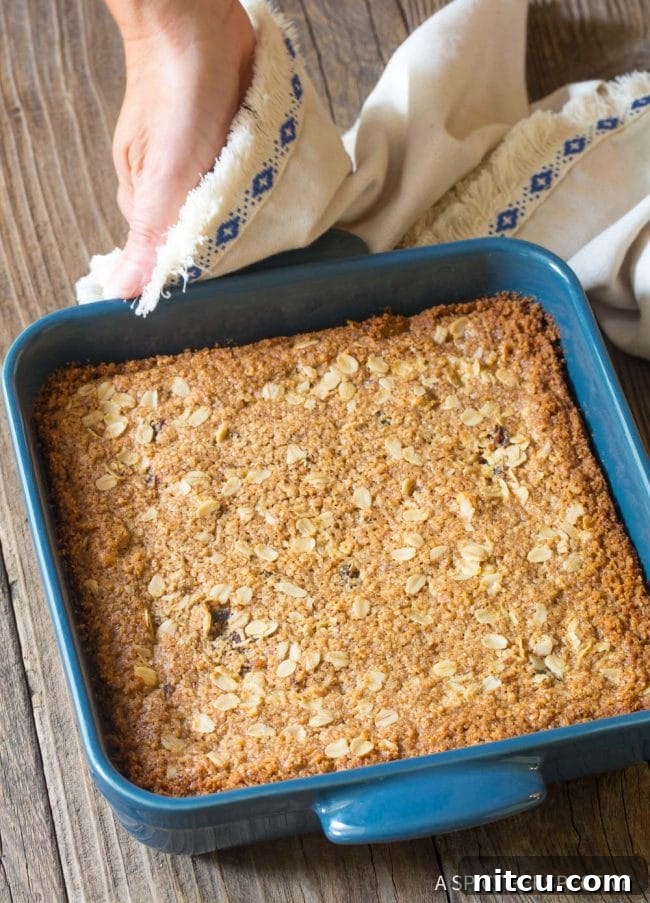 A full pan of freshly baked oat bars in a blue baking dish, golden brown and ready to cool.
