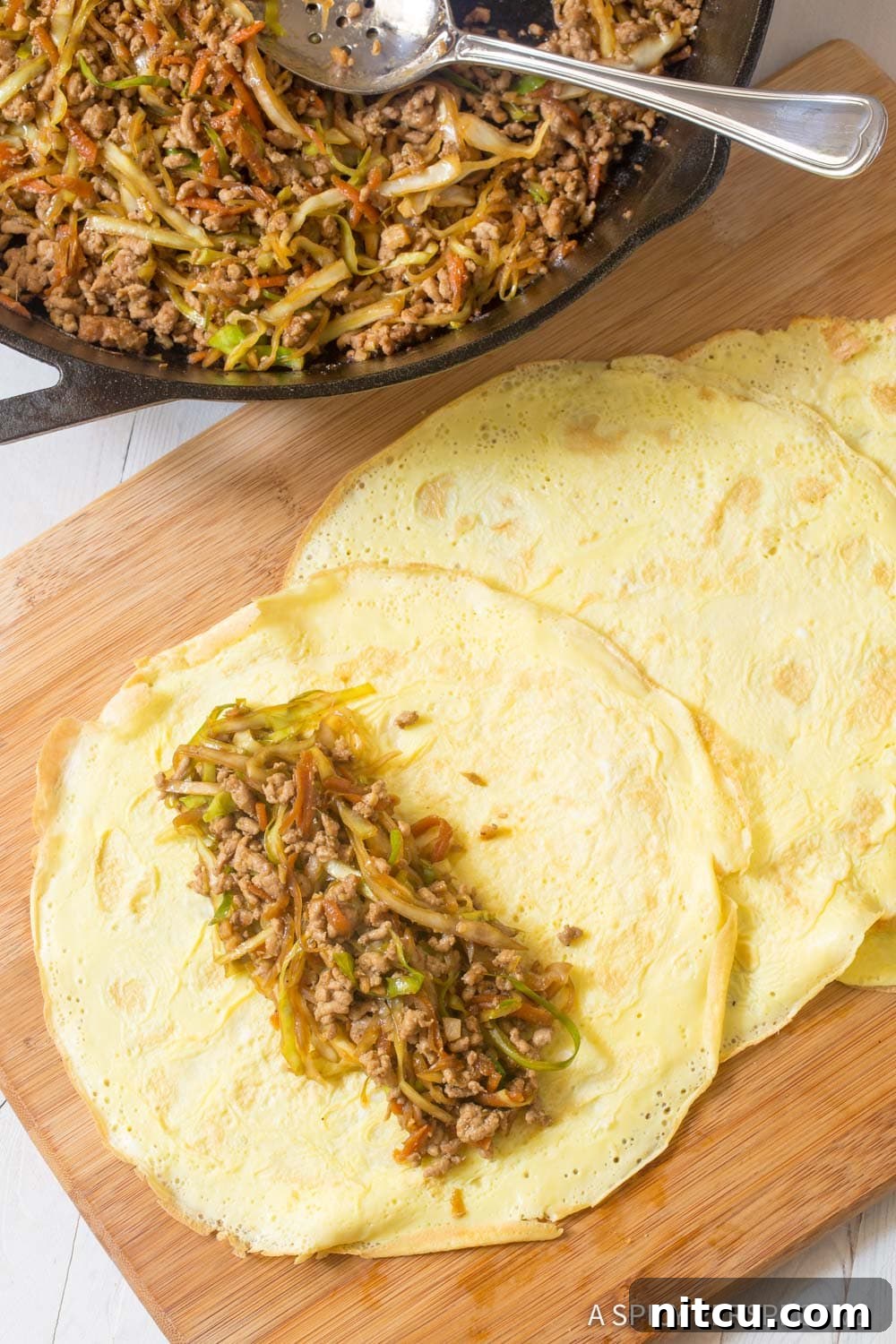 Laid out egg wrap filled with pork filling. 