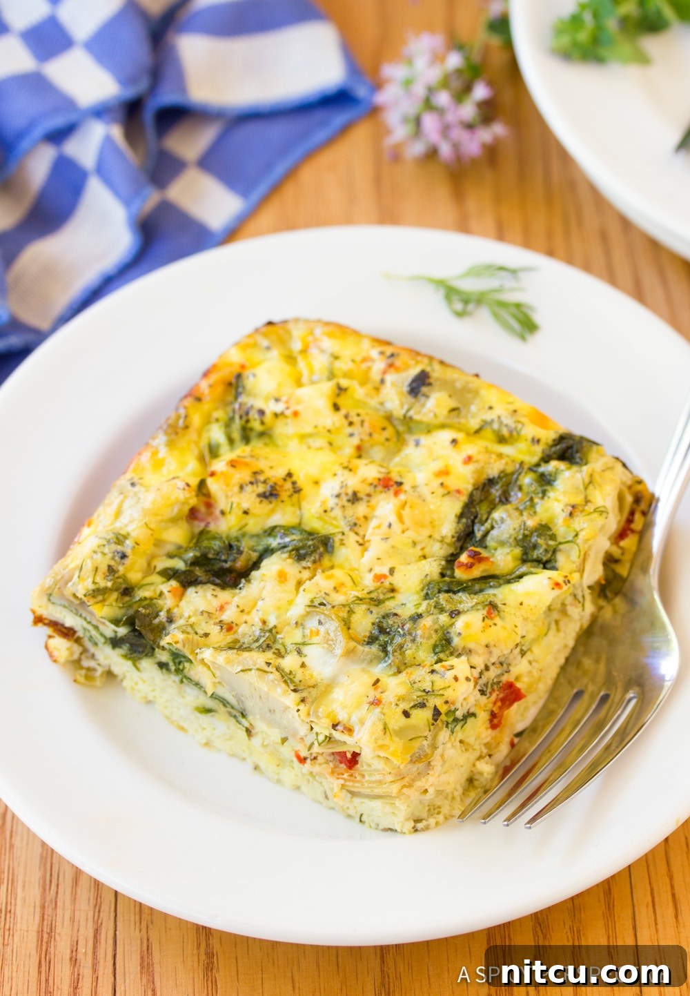 A beautifully presented slice of Greek omelette casserole on a white plate, garnished with fresh herbs, ready to be enjoyed.
