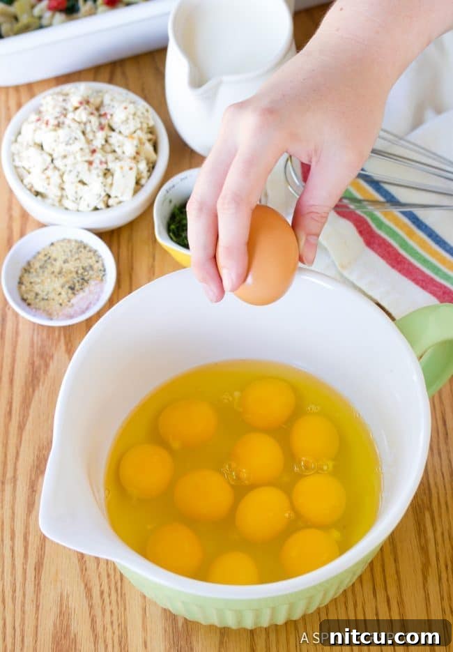 A close-up of a hand cracking a fresh egg into a white mixing bowl, ready for whisking.