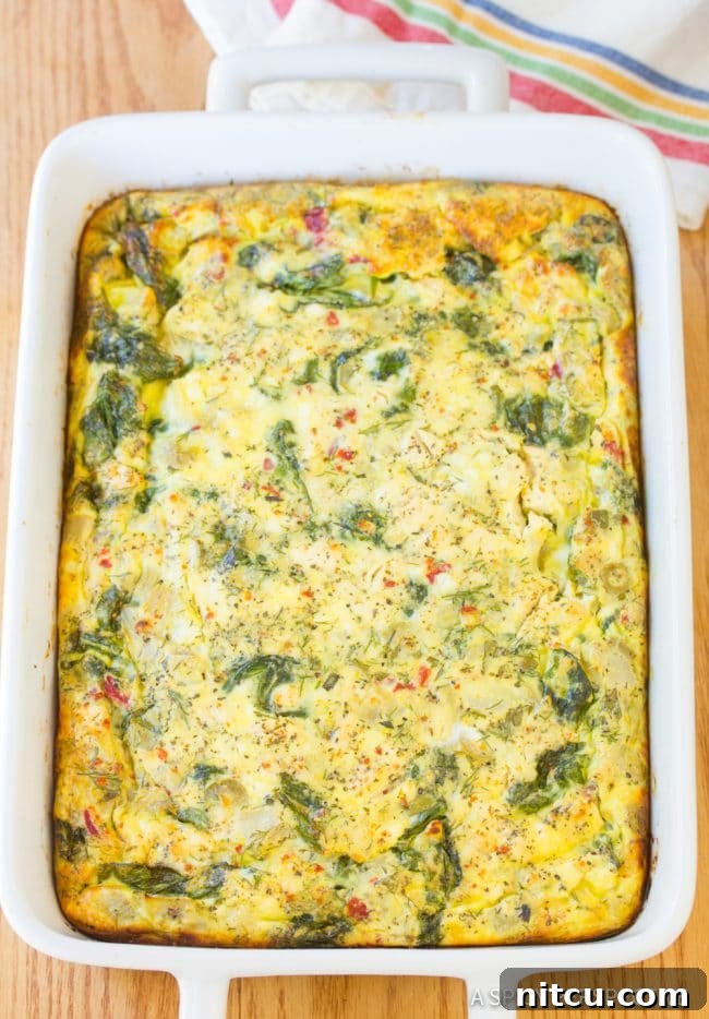 A golden-brown baked Greek omelette casserole, hot and ready to be served from its dish.