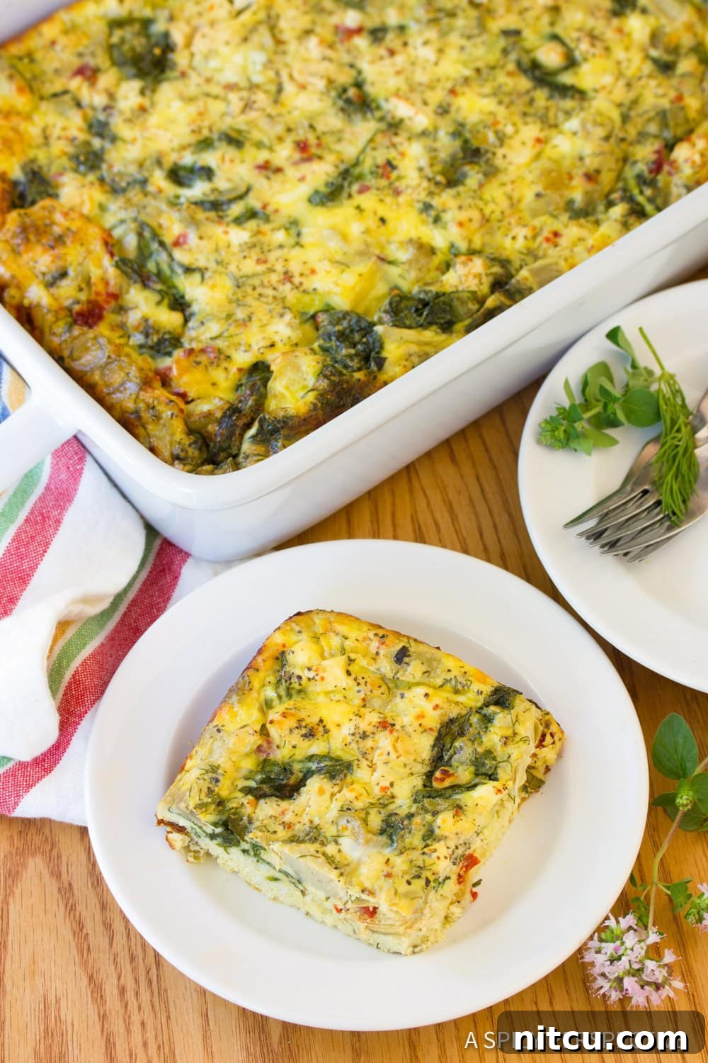 A perfectly portioned slice of Greek omelette casserole on a white plate, showcasing its fluffy texture and colorful ingredients.