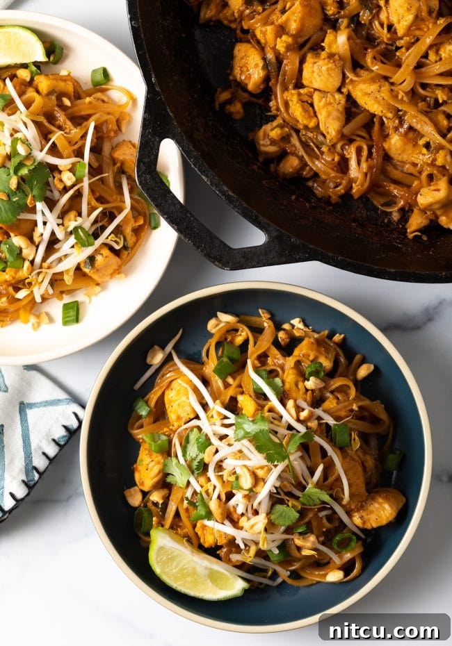 Overhead shot of Pad Thai noodles in a bowl garnished with mung bean sprouts, lime wedges, and fresh cilantro, showcasing its vibrant freshness.