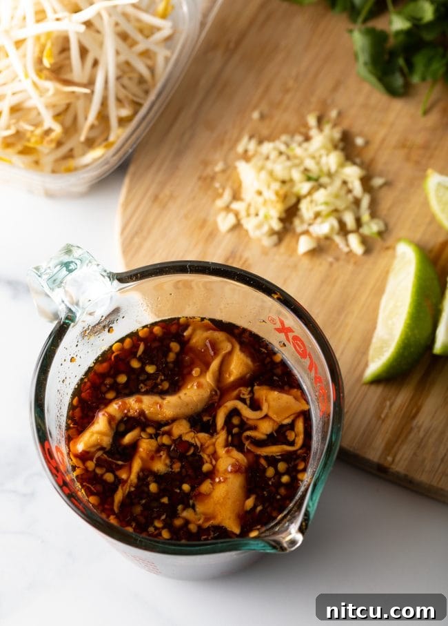 Top-down view of sauce ingredients meticulously blended in a glass measuring cup, ready for the Pad Thai stir-fry.
