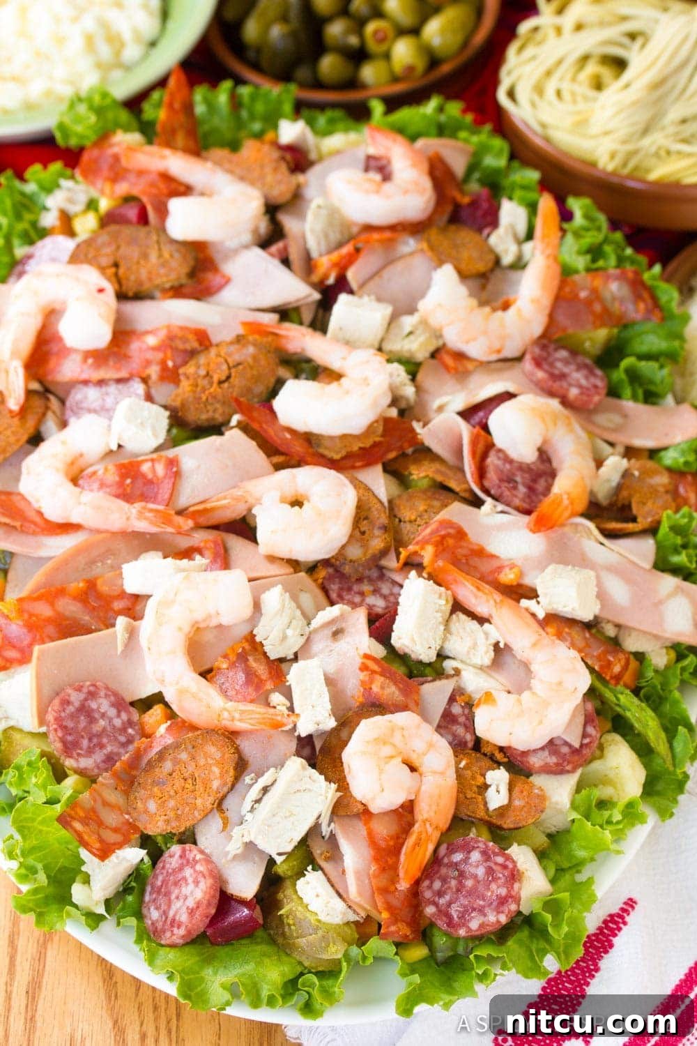 A plate of assorted cured meats and shrimp arranged on a bed of fresh lettuce, ready for the Fiambre salad.