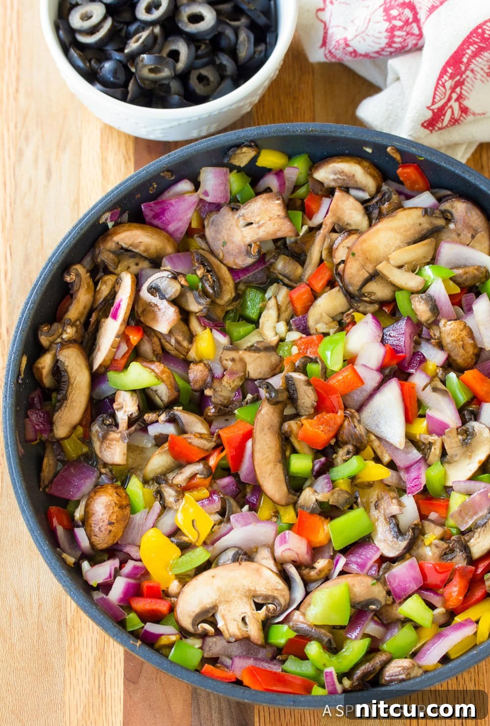 A close-up shot of colorful bell peppers, onions, and mushrooms sautéing lightly in a skillet, filling the pan with vibrant ingredients and a tantalizing aroma.