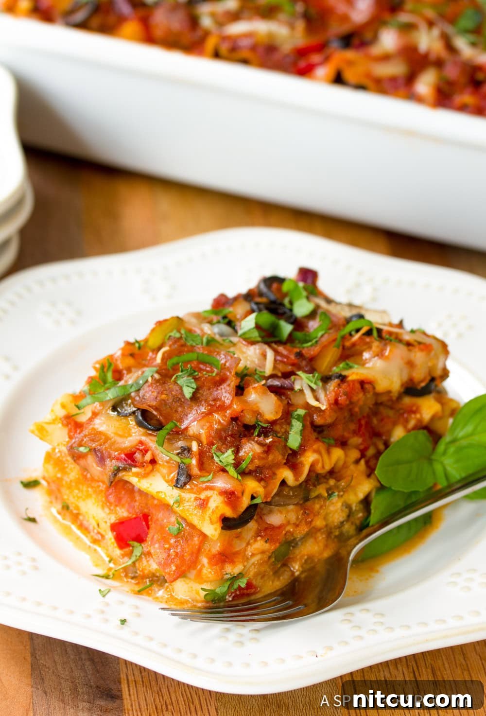 A perfect, golden-brown slice of Supreme Pizza Lasagna elegantly plated, showcasing its distinct layers and tempting toppings.