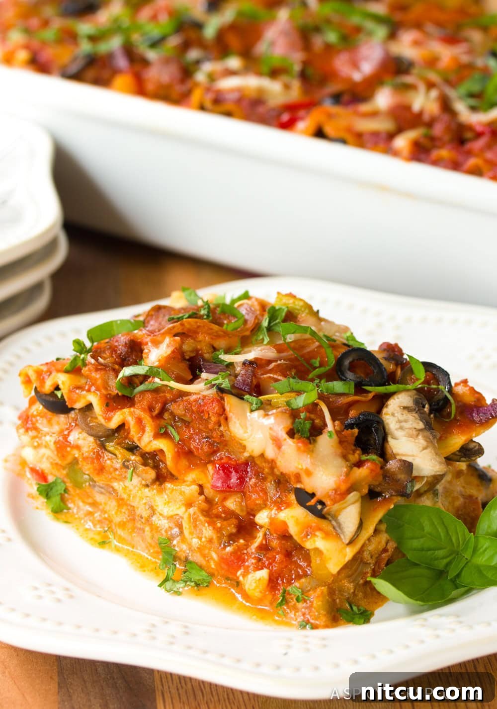 A tempting, golden-brown slice of Supreme Pizza Lasagna, generously topped with melted cheese and pepperoni, beckons from a white plate.