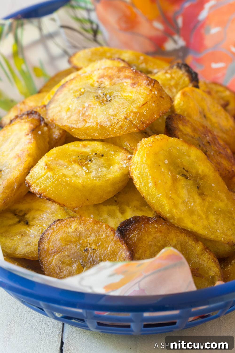 A rustic basket overflowing with golden-brown baked plantains, highlighting their tender texture and slightly crisp edges.