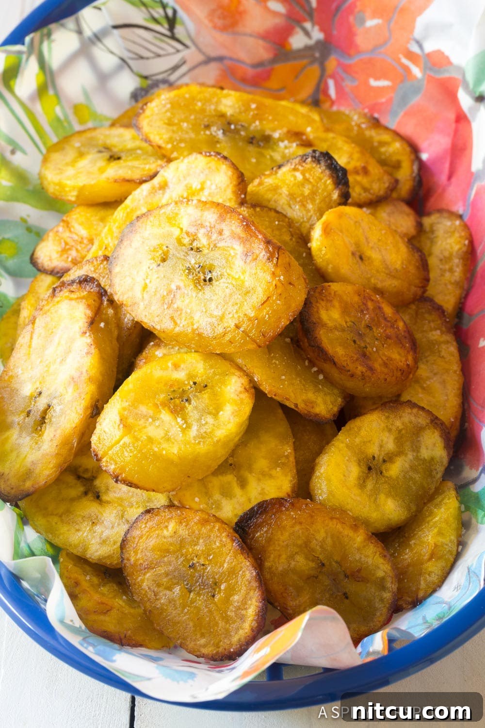A woven basket filled with freshly baked, golden-brown crispy plantains, ready to be enjoyed as a snack or side.