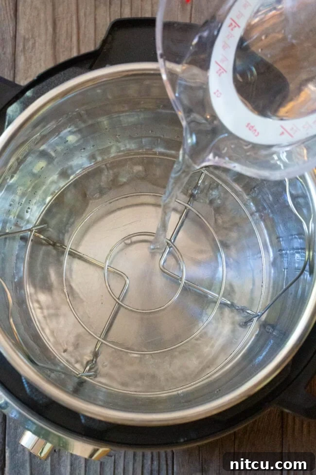 Pouring water into the Instant Pot base, preparing for pressure cooking the quiche in a water bath.