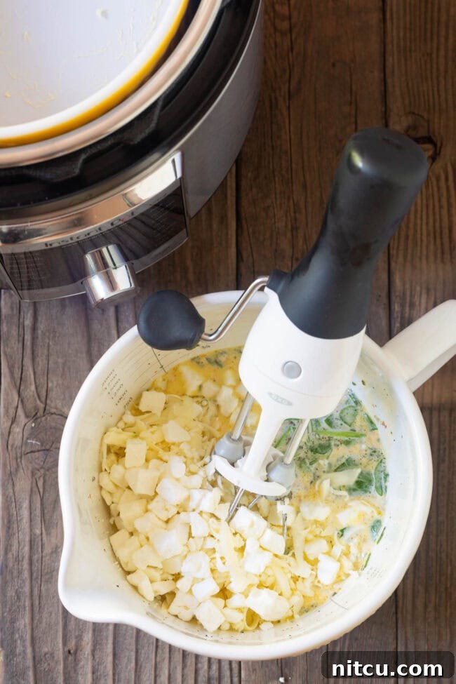 Mixing bowl with quiche ingredients being whisked together by an electric mixer.