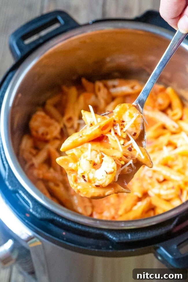 Shrimp pasta in an instant pot with a spoon hovering over it with a bite of pasta. 