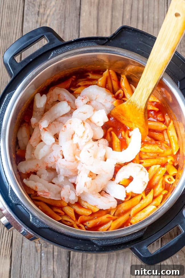 Shrimp being added to the pasta and sauce. 