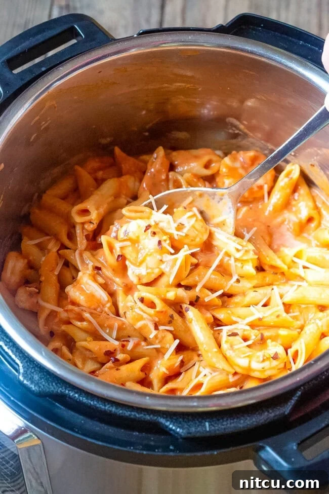 Shrimp pasta with vodka sauce in an instant pot with a spoon in the pot. 