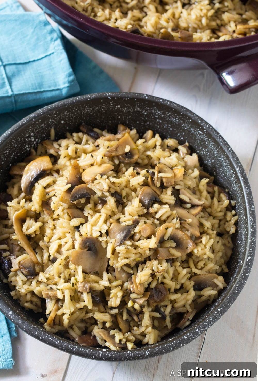 A black bowl filled with savory mushroom rice pilaf, garnished with fresh herbs, ready to be enjoyed.