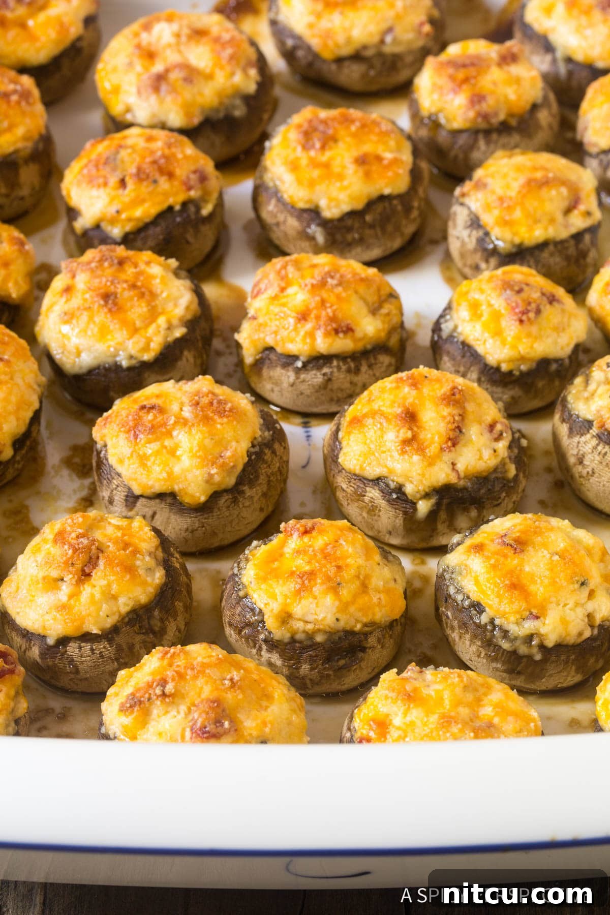 A dish brimming with perfectly baked, golden-brown cheesy stuffed mushrooms, ready to serve as a delicious appetizer.
