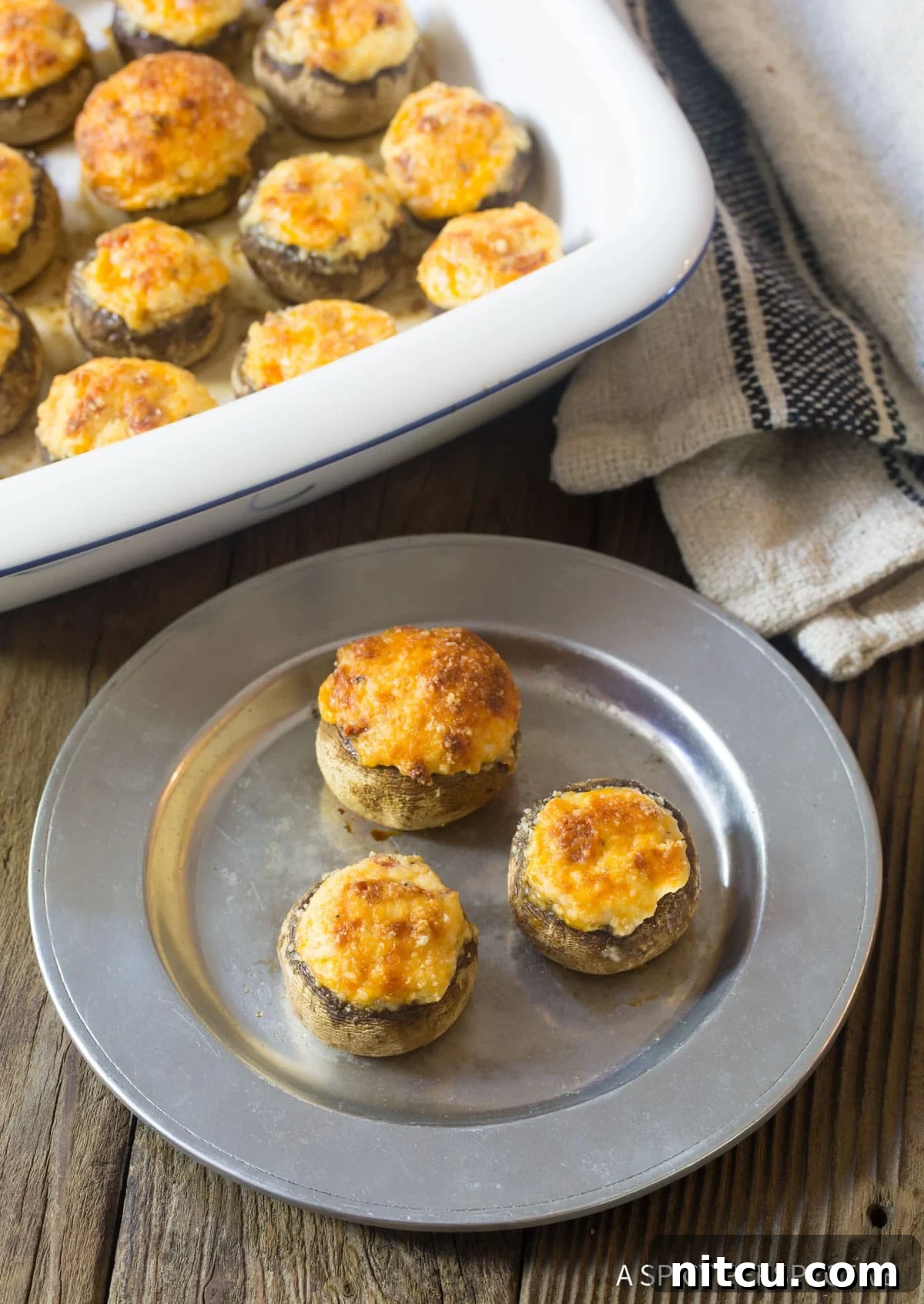 An appetizer plate showcasing several cream cheese stuffed mushroom caps, enticingly golden and bubbly.