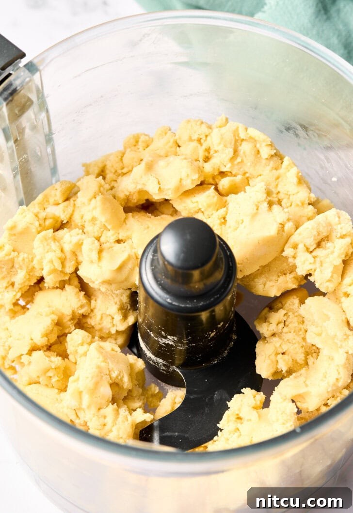 Mini Apple Pies Recipe - close-up of dough being mixed in a food processor, highlighting the cornmeal for the crust.