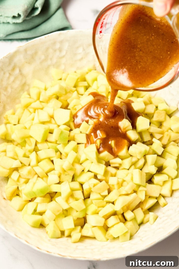 Pouring rich brandy-infused syrup over freshly diced apples for the pie filling, creating an intoxicating aroma.