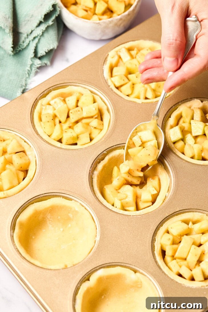 Mini Apple Pie Recipe - filling the prepared cornmeal pie crusts in a muffin tin with the rich apple mixture.