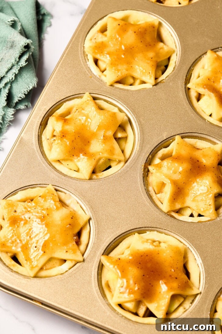 Mini Apple Pie - decorative crust topping being placed on each pie before baking.