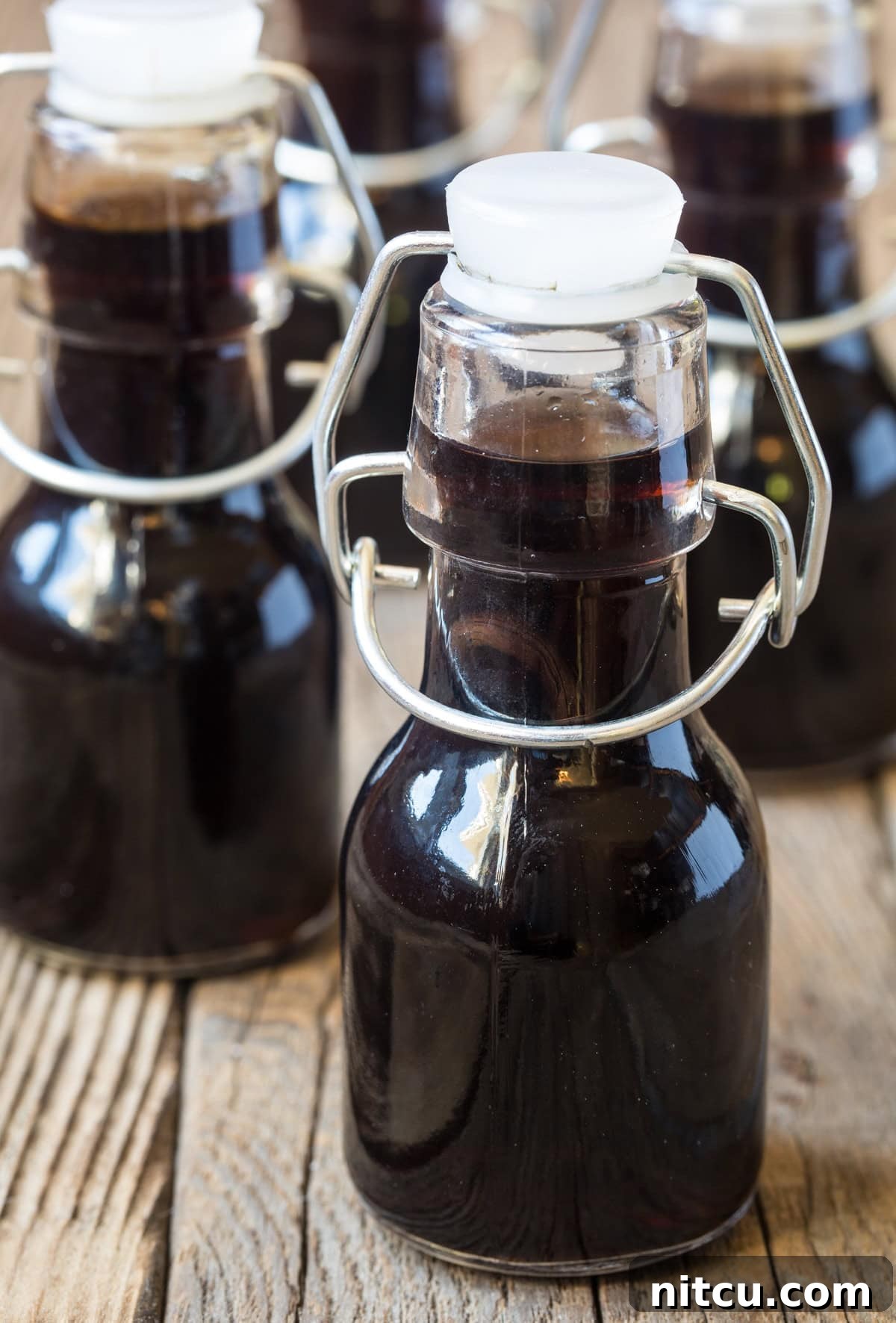 Little bottles of homemade vanilla on a wooden surface.