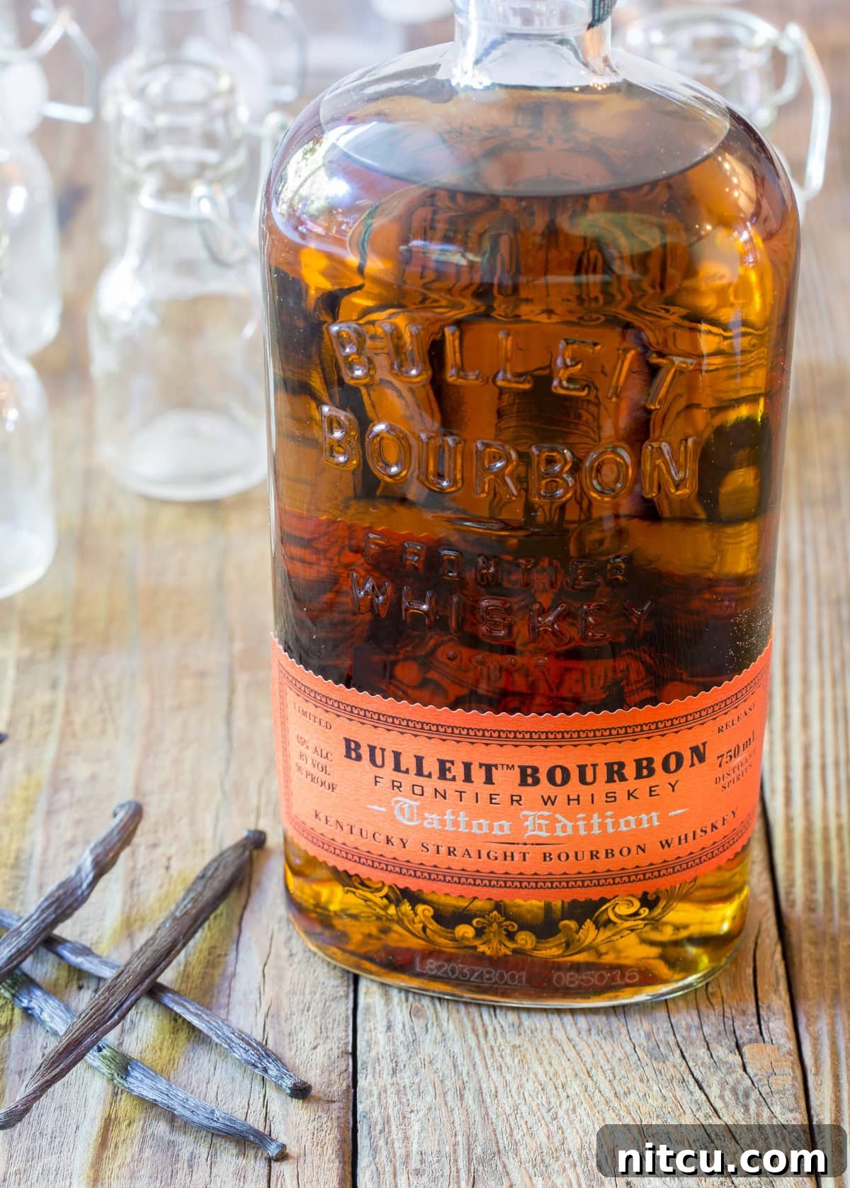 Bottle of bourbon with vanilla pods next to it.