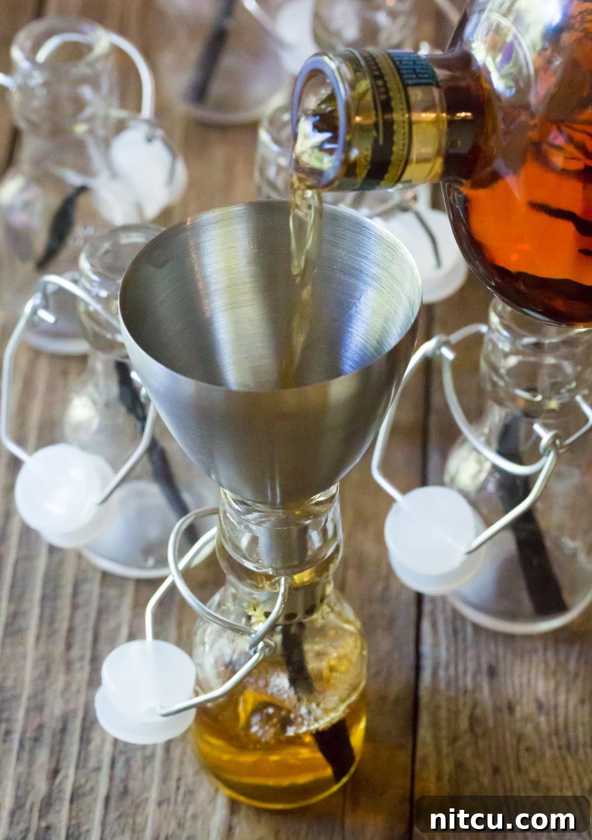 Pouring bourbon into the small bottles using a funnel.