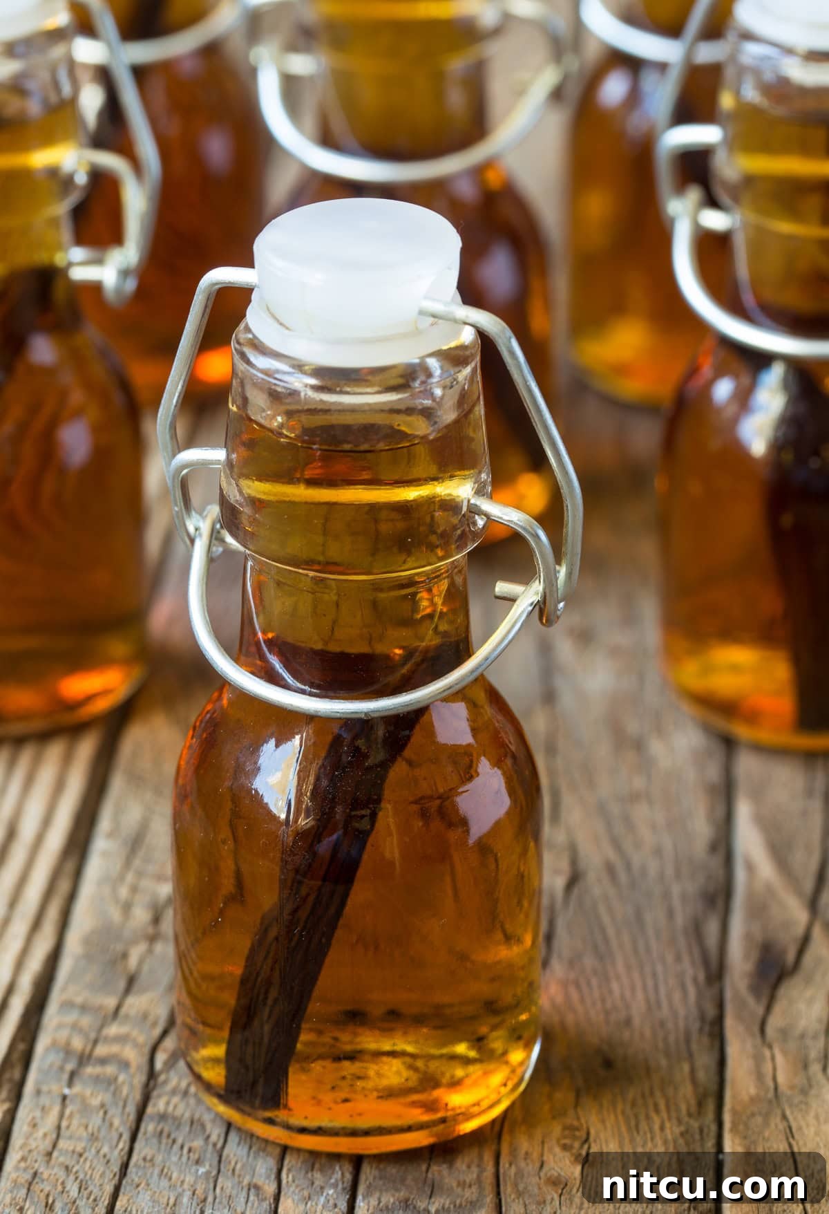 Close up shot of a small bottle of homemade vanilla extract with more bottles in the background.