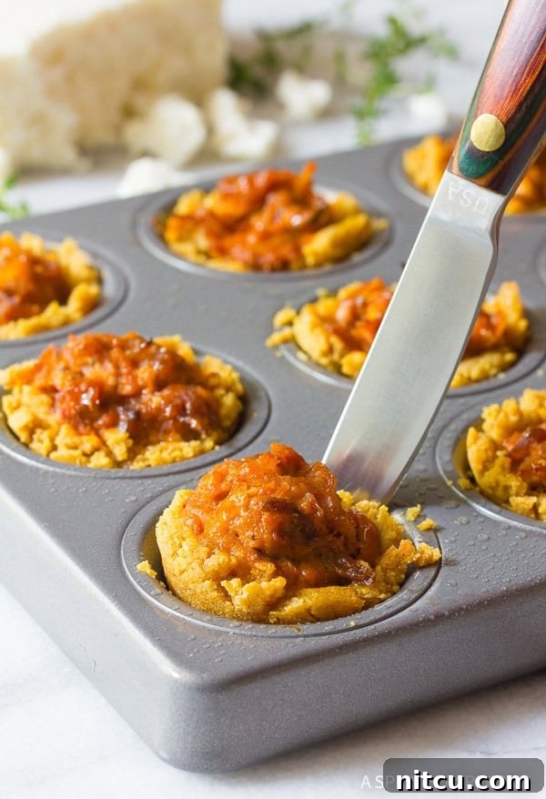 Warm, baked mini tamales being gently removed from a baking sheet, showcasing their perfect shape.