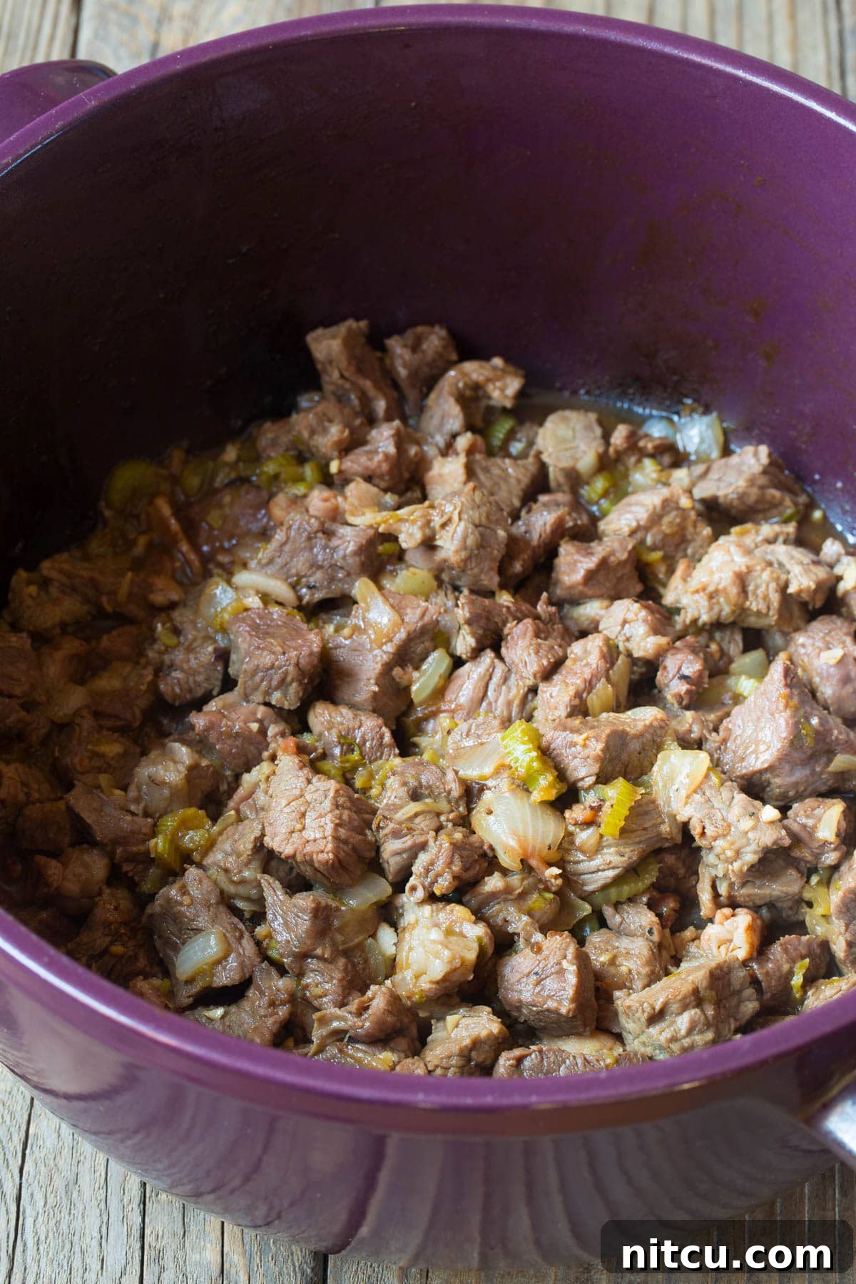 Beef being perfectly seared and browned in a pot with vegetables.