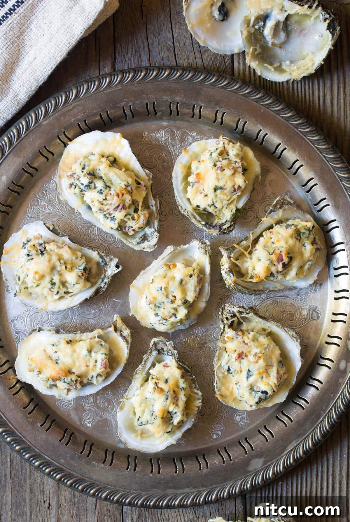 Overhead view of cheesy baked oysters on the half shell, arranged on a baking tray
