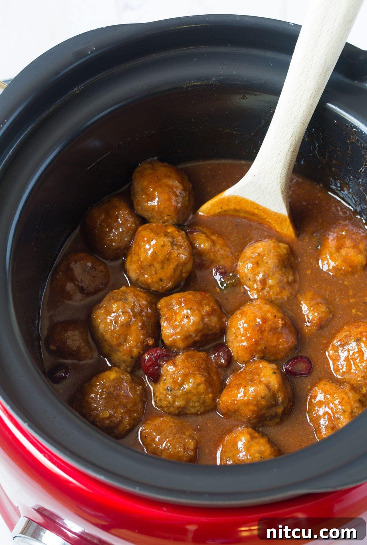 Top view of delicious crock pot barbecue meatballs with a wooden spoon stirring them