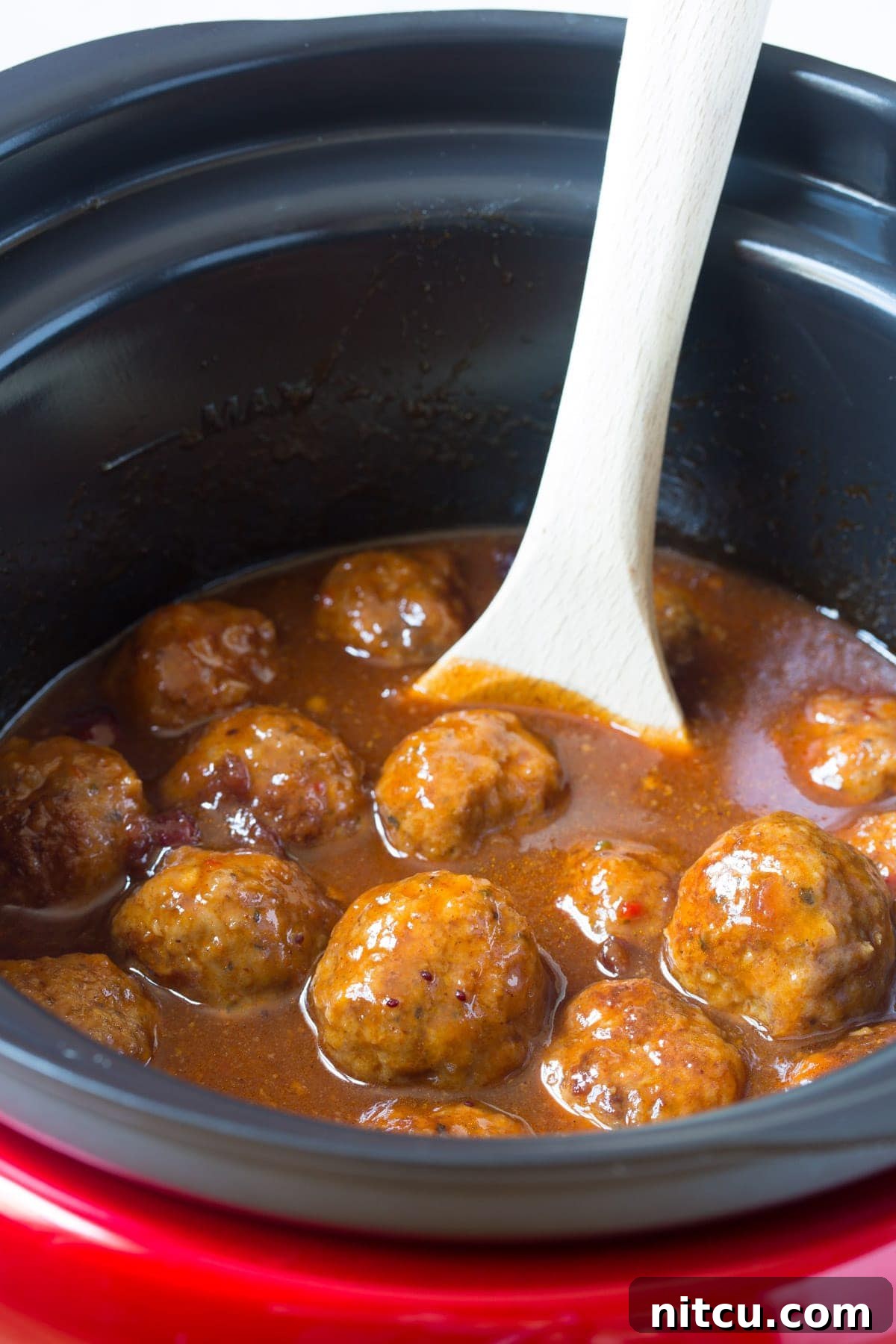 Crock pot cocktail meatballs simmering gently in their sweet and spicy sauce