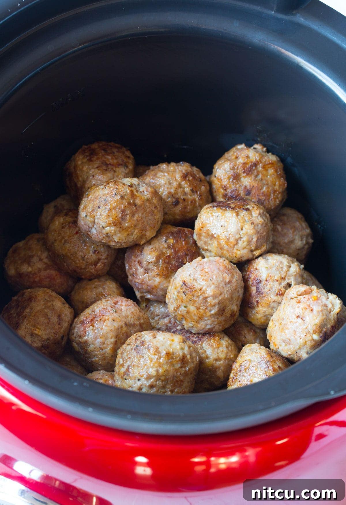 Placing either homemade or frozen meatballs into the slow cooker for simmering