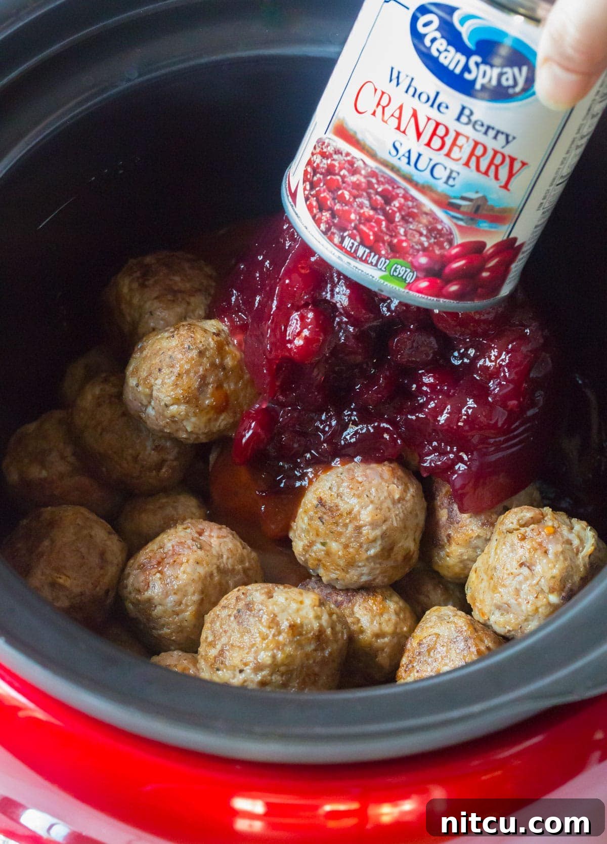 Adding canned whole cranberry sauce over the main ingredients in the Crock-Pot