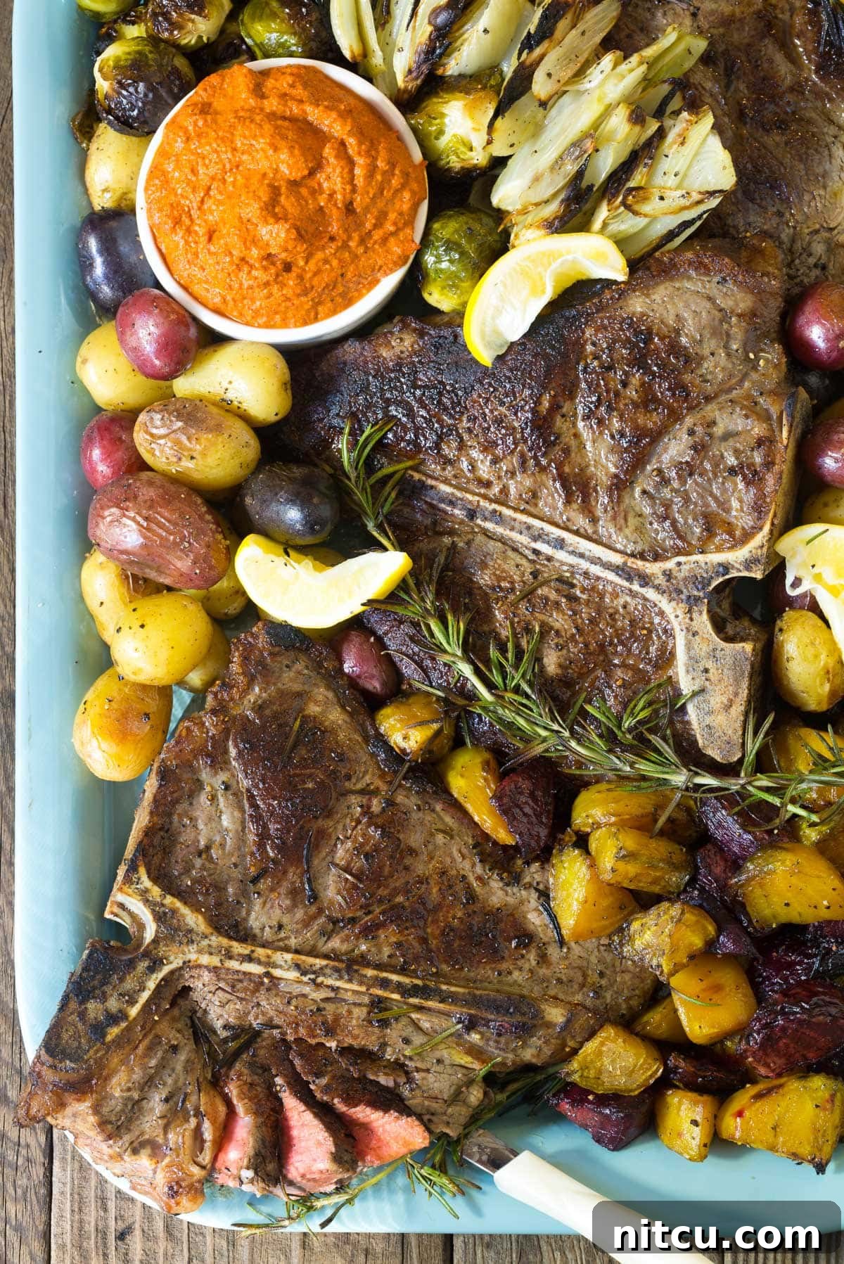 Italian Bistecca alla Fiorentina Recipe (Florentine Steak) on a large platter with roasted vegetables and Romesco sauce