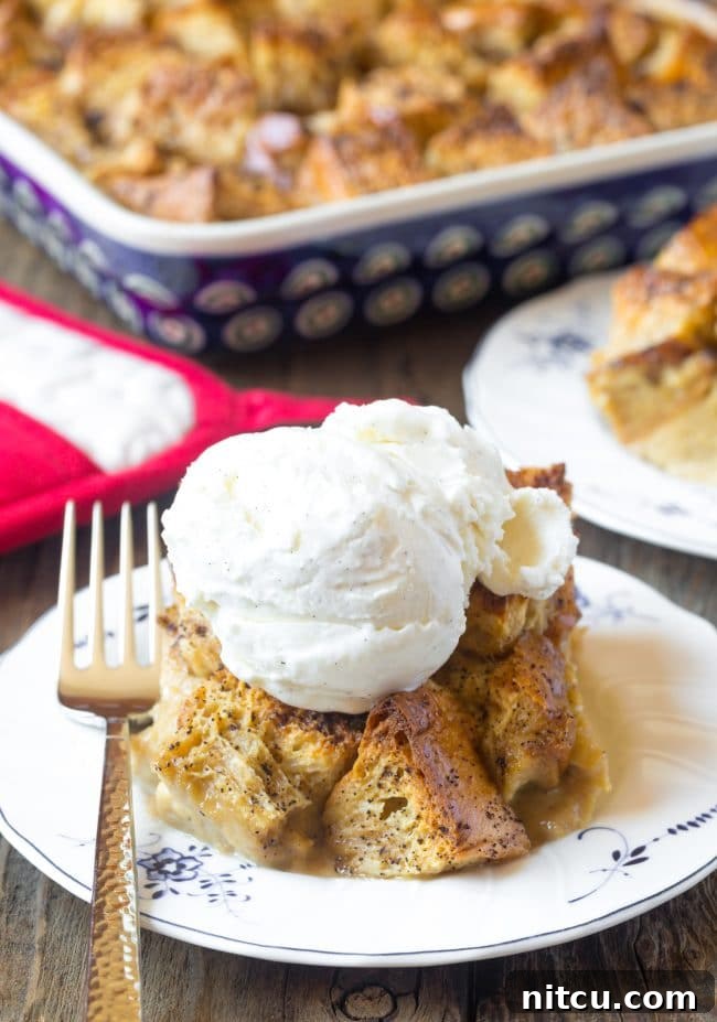 Piece of bread pudding topped with a scoop of ice cream on a white plate.
