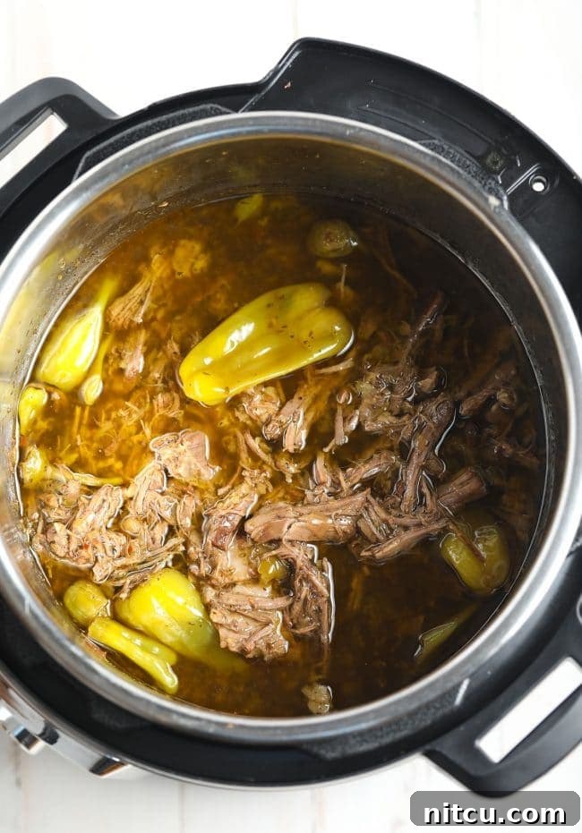 Shredded Low Carb Instant Pot Italian Beef with cooking juices in the pot.