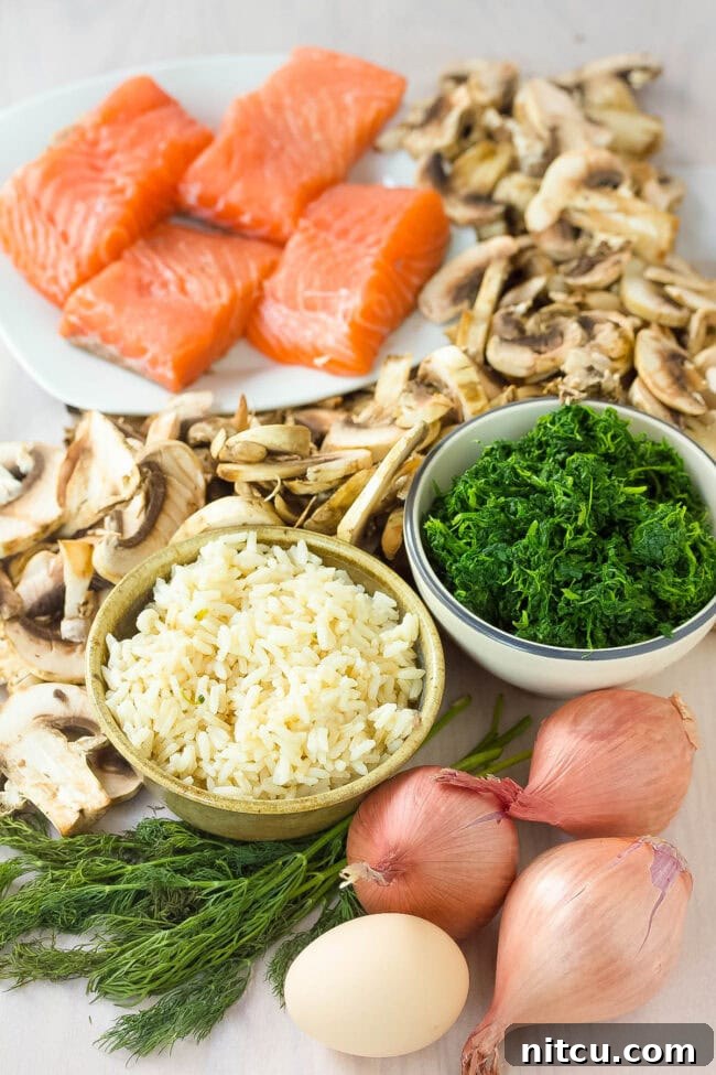 A collection of fresh ingredients laid out for making Salmon Wellington, including salmon fillets, puff pastry, mushrooms, spinach, and dill.